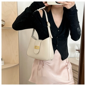 Detail of minimalist cream leather underarm bag with golden metal buckle and strap