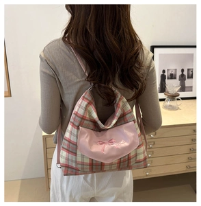 Detail of pink plaid backpack featuring bow embroidery on a leather pocket cover