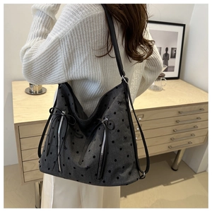 Detailed view of polka dot embroidered shoulder bag with bow ties and dual zipper pockets