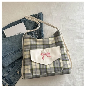 Detail of plaid canvas tote bag with leather pocket and pink bow embroidery