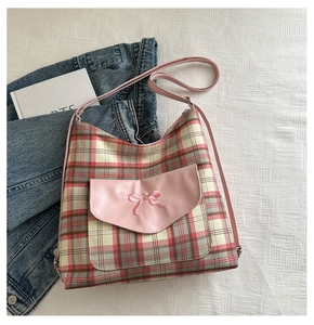 Close-up of pink plaid tote bag featuring a leather pocket with bow embroidery detail