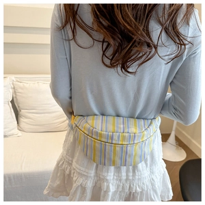 Détail d'un sac banane demi-lune à rayures avec sangle réglable porté en bandoulière