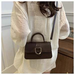 Deep brown PU leather crossbody bag with iconic gold D-ring buckle shown on model