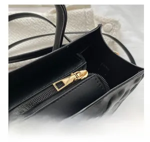 Close-up of golden metal zipper on black litchi textured leather handbag detail