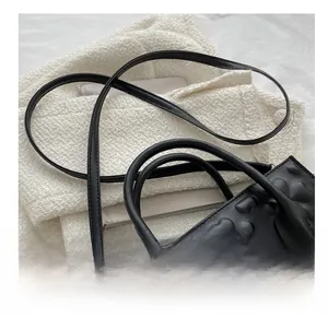 Detail of adjustable black leather strap with gold buckle and heart embossed texture