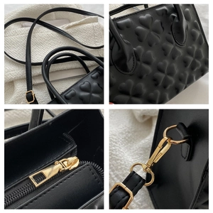 Detail showing 3D embossed clover texture, golden hardware, and strap of black leather bag