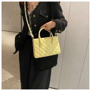 Detail of light yellow handbag with heart-shaped embossing and slender shoulder strap