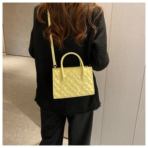 Detail of yellow heart-quilted crossbody bag on a model wearing a black coat