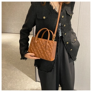 Brown leather handbag with heart embossing, featuring dual handles and thin shoulder strap