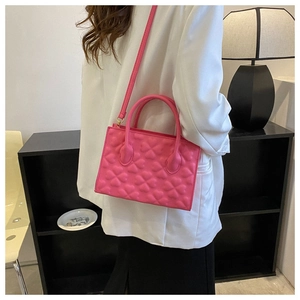 Detail of rose pink handbag featuring heart-shaped embossed texture and dual handles