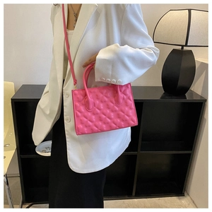 Detail of fuchsia leather handbag with embossed heart pattern and stylish double handles