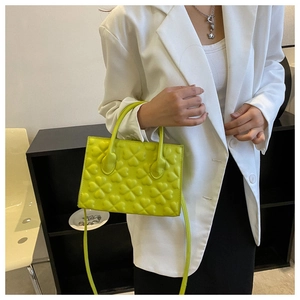 Detail view of the fluorescent green clover embossed mini handbag with a white blazer