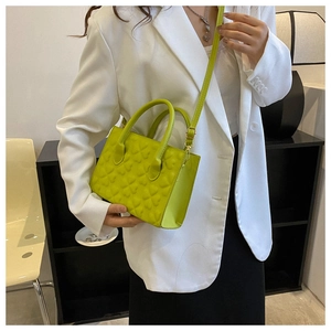 Detail of neon green handbag with 3D heart embossing and stylish gold hardware accents