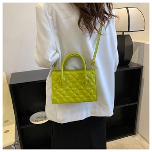 Detail of vibrant green clover-embossed handbag with smooth PU leather and top handle