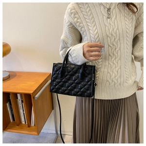 Detail of black crossbody bag with embossed heart pattern on synthetic leather material