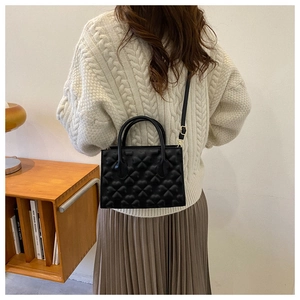 Chic black clover quilted handbag with dual handles and adjustable shoulder strap for women