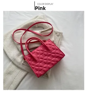 Detailed close-up of pink crossbody bag with embossed heart patterns and leather strap