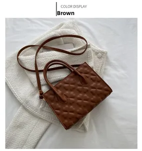 Detailed view of brown handbag with clover embossing on white textured fabric background