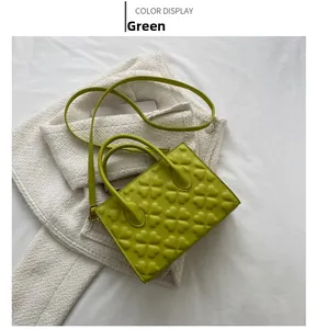 Detailed view of green matte leather handbag with embossed clover patterns and top handle