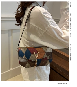 Detail of color-block geometric handbag showing textured leather and V-shaped gold hardware