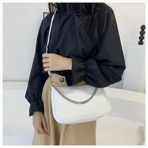 Détail du sac demi-lune blanc avec chaîne argentée porté par un mannequin en décor épuré
