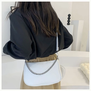 Vue arrière du mannequin portant un sac baguette blanc avec chaîne en métal gris foncé