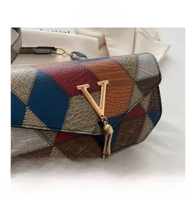 Detail of color-block bag with crocodile texture, gold V-clasp and tassel detail