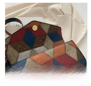 Detail view of the magnetic gold buckle and textured leather stitching on a colorful bag