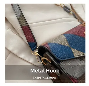 Detail of golden metal hook and geometric color-block leather on small square bag