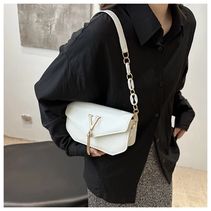 Detail of white leather shoulder bag featuring gold V logo and elegant metallic tassels