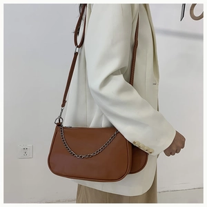 Sac baguette en cuir marron avec chaîne argentée porté par un mannequin pour l'échelle