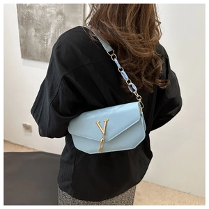 Detail of light blue crossbody bag with gold V logo and tassel on elegant flap cover