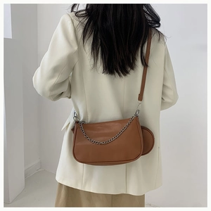 Sac baguette en cuir marron avec chaîne argentée et petite pochette sur mannequin en blazer