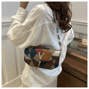 Detail of color-block bag featuring V-shaped gold clasp and chain tassel decoration