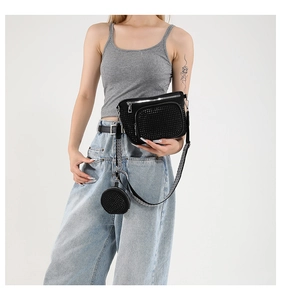 Détail d'un sac bandoulière en strass noirs avec large sangle et mini pochette sur mannequin