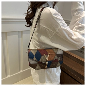 Chic geometric patchwork shoulder bag with metal V-buckle on white shirt model