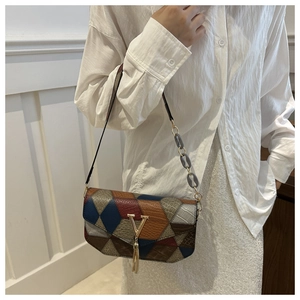 Detail of color-block flap bag featuring crocodile texture and gold V-shaped metal hardware