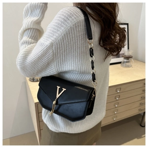 Detail of black leather flap shoulder bag with gold V-shape logo and tassel charm
