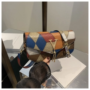 Detail of color-block square bag showing mixed textures, V logo, and tassel charm