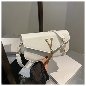 Close-up of white leather handbag featuring gold V-shaped hardware and elegant fringe detail