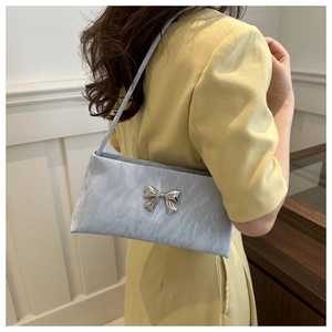 Light blue pleated underarm bag with silver bow buckle worn by a female model