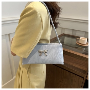 Detail of light blue pleated shoulder bag with a silver bow knot on yellow dress