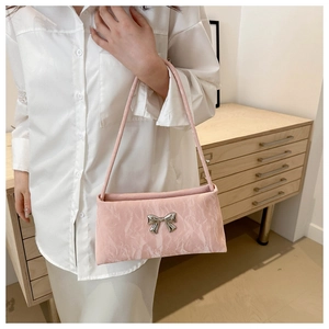 Close-up of pink pleated shoulder bag featuring a decorative silver metallic bow detail