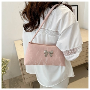 Pink pleated shoulder bag with silver bow accent shown in a stylish home setting