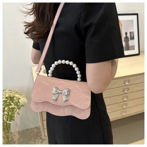 Pink patent leather handbag with pearl handle and silver bow in home setting