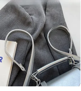 Close-up of the smooth adjustable shoulder strap and leather handle on the silver bag
