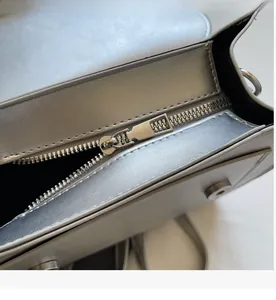 Detailed close-up of smooth silver metal zipper and hardware on the vintage square bag