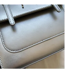 Macro shot of fine leather texture and stitching detail on the silver-grey handbag