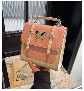 Close-up of the elegant silver butterfly buckle and pink suede contrast on the small square bag