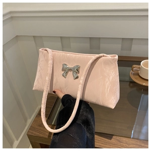Close-up of light pink pleated fabric shoulder bag with a silver metal bow detail